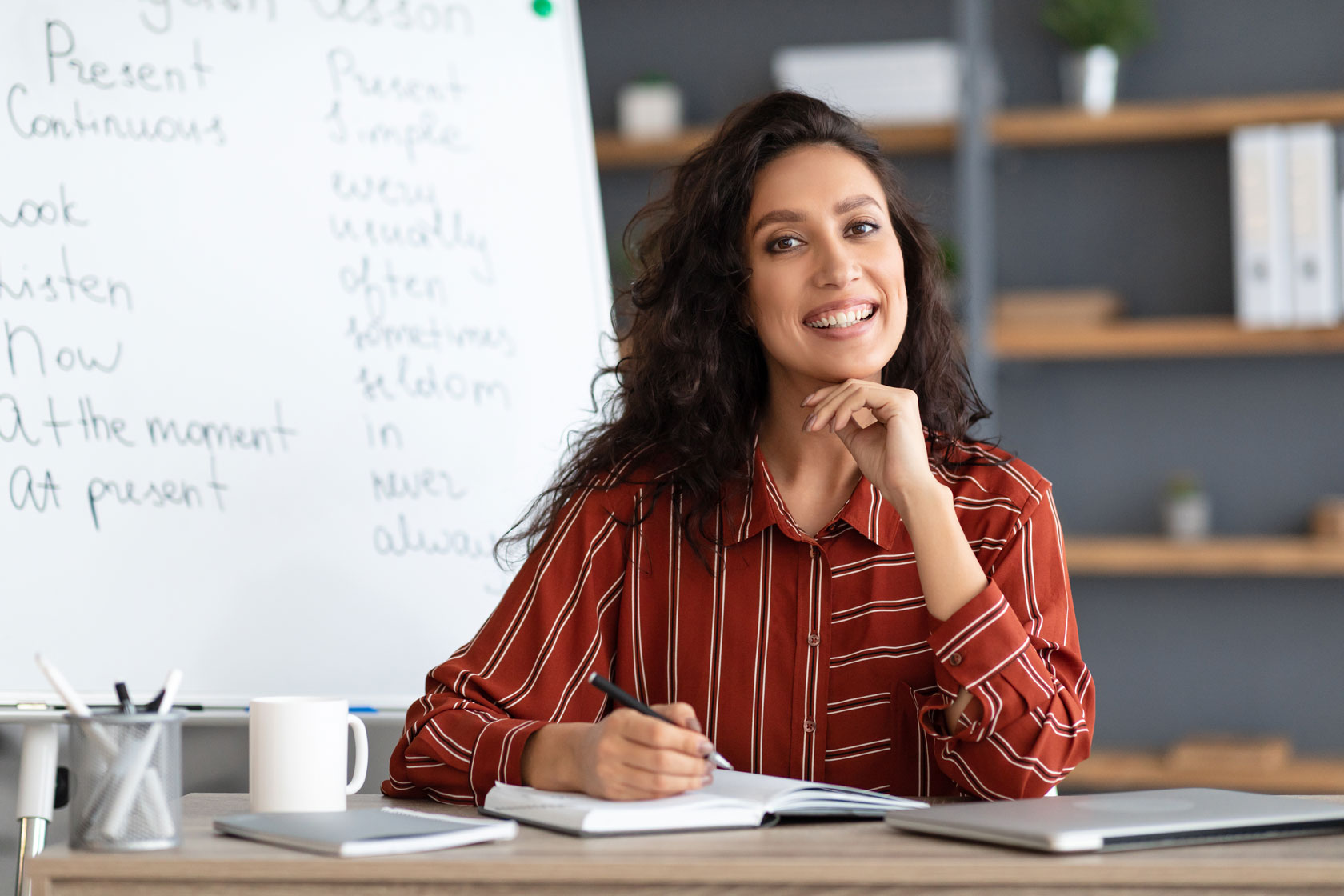 female-teacher-sitting-at-desk-looking-at-camera